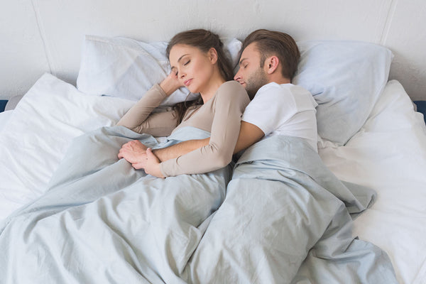Young couple snuggling and sleeping restfully in bed