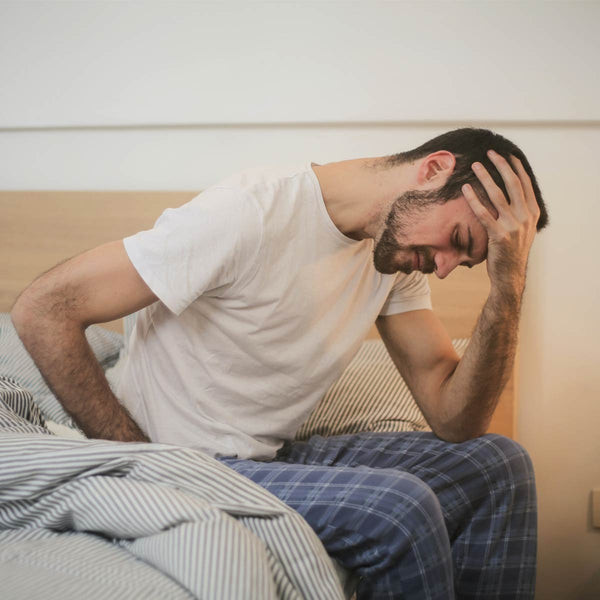 Man waking up tired with a headache first thing in the morning