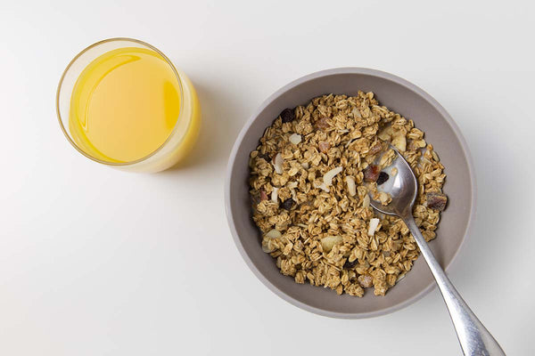 A high-fiber breakfast of granola in a bowl and orange juice in a glass