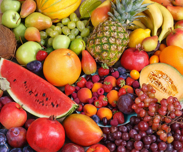 An assortment of superfruits, including pineapple, berries, melon, pomegranate, and grapes